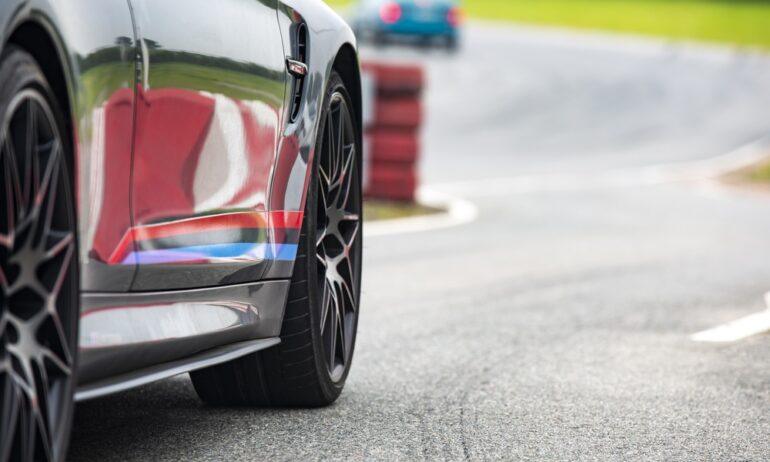 The lower exterior and wheels of a modern performance car approaching a corner at a professional race track.